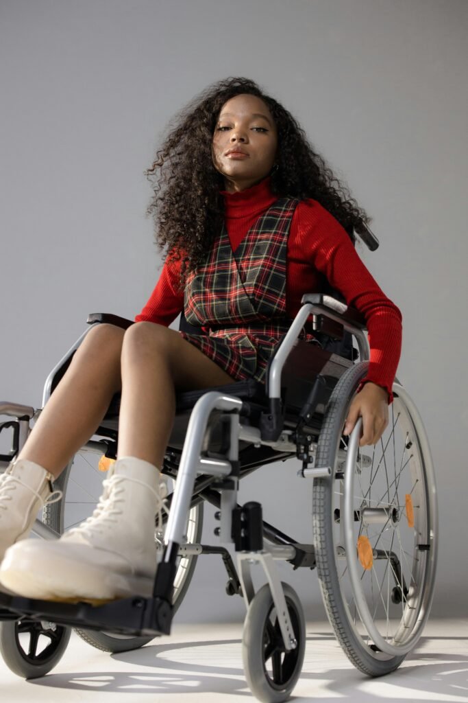 Portrait of a confident black woman in a wheelchair, wearing a plaid dress and red turtleneck, showing empowerment.